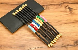 Detalle de dijes Evil Eye coloridos en pulseras de cuero trenzado negro con cierres magnéticos