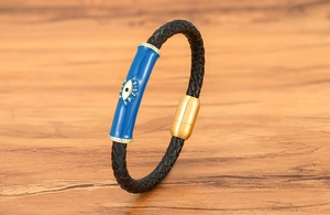 Detalle del dije de ojo turco azul en una pulsera de cuero trenzado negro con cierre dorado