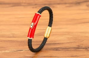 Detalle de pulsera de cuero trenzado negro con amuleto ojo turco rojo y cierre magnético
