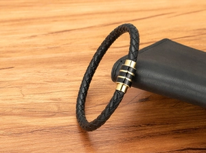 Détail d'un bracelet en cuir tressé pour homme avec fermoir magnétique doré sur cuir