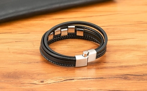 Detail eines mehrlagigen schwarzen Lederarmbands mit gebürstetem Magnetverschluss aus Stahl