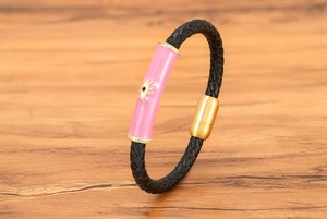 Detalle del amuleto ojo turco en esmalte rosa y circonitas en pulsera de cuero trenzado