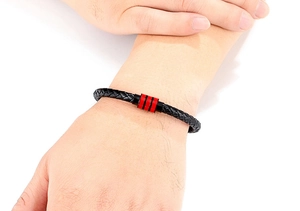 Gros plan du bracelet pour homme en cuir tressé noir avec détail en métal rayé rouge