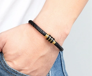 Détail du bracelet en cuir noir tressé pour homme avec accents métalliques dorés