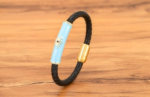 Detalle de pulsera de cuero con ojo malvado y cierre dorado sobre madera