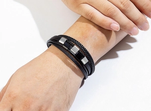 Detail eines mehrlagigen schwarzen Lederarmbands mit Magnetverschluss aus Edelstahl