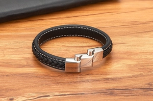 Macro detail of braided leather bracelet featuring a silver brushed metal interlocking clasp