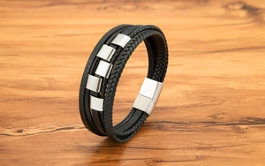 Detail eines mehrlagigen Lederarmbands mit gebürstetem silbernem Magnetverschluss auf Holz