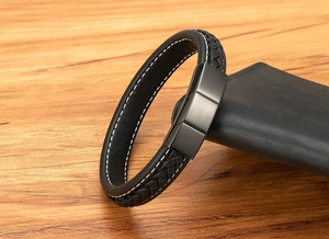 Detail of woven black leather bracelet with white stitching and matte magnetic metal clasp