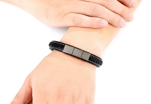 Macro detail of men's braided leather bracelet with white stitching and magnetic clasp