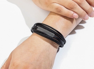 Detailed macro view of multilayer black leather woven bracelet with silver mesh metal plate