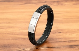 Close-up of black braided leather bracelet with silver magnetic clasp and white stitching