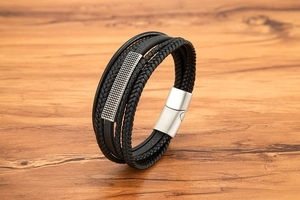 Detail of multi-strand black leather braid bracelet with textured metal bar and magnetic clasp