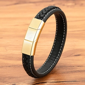 Braided black leather bracelet for men with golden magnetic clasp on wood surface