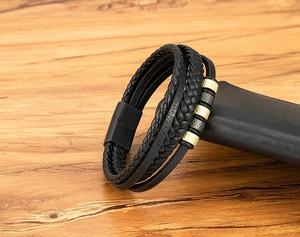 Détail d'un bracelet multicouche en cuir noir tressé avec fermoir magnétique et perles en métal