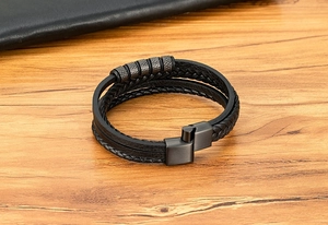 Détail d'un bracelet en cuir noir multicouche avec des perles en acier inoxydable gravées