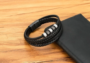 Détail d'un bracelet en cuir tressé multicouche avec perles métalliques sur un portefeuille