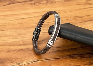 Macro-opname van bruine gevlochten leren armband met roestvrijstalen sluiting op houtdecor
