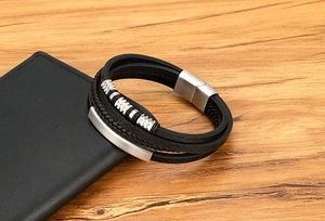 Detail eines Herren-Mehrschicht-Lederarmbands mit silbernen Metallperlen auf Holztisch