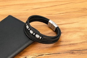 Detalle de pulsera de cuero multicapa sobre una cartera con cierre magnético cepillado