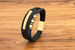 Nahaufnahme von schwarzem Lederarmband mit goldener Metallplatte und Magnetverschluss