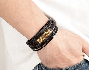 Dettaglio del bracciale in pelle multistrato con cuciture rosse e fibbia in oro opaco