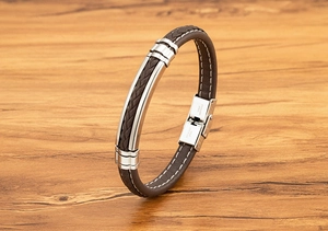 Detail van bruine gevlochten leren armband met stalen sluiting op houten achtergrond