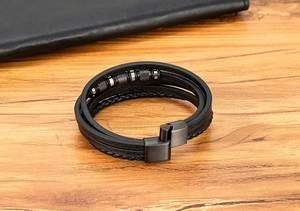 Detalle de una pulsera multicapa de cuero trenzado negro con cuentas de acero e imán de cierre