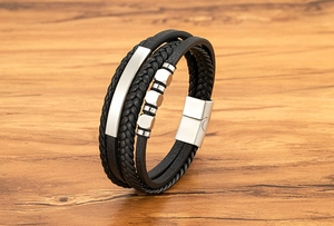Detail eines schwarzen Lederarmbands mit silbernem Magnetverschluss auf Holzhintergrund