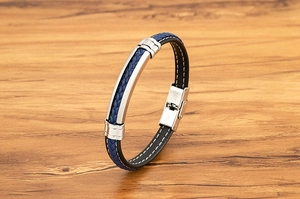 Detail van blauwe gevlochten armband met roestvrijstalen bar op houten achtergrond