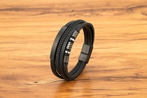 Detail eines mehrlagigen Herrenarmbands aus schwarzem Leder mit matter Metallplatte