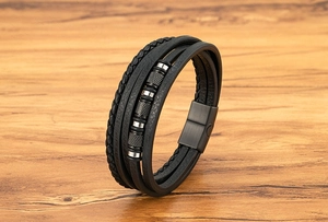 Detalle de pulsera de cuero trenzado multicapa con cuentas de metal moleteado y cierre magnético
