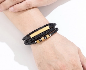 Detailansicht eines mehrlagigen schwarzen Lederarmbands mit goldener polierter Metallplatte