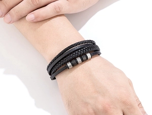 Gros plan d'un bracelet multicouche en cuir noir pour homme avec perles métalliques au poignet
