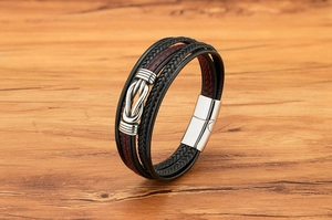 Dettaglio del bracciale multistrato in pelle da uomo con cuciture rosse e chiusura argento