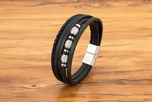 Detalle de pulsera de cuero negro de varias capas con cuentas metálicas plateadas
