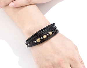 Primer plano de pulsera de cuero trenzado negro para hombre con cuentas doradas y cierre de metal