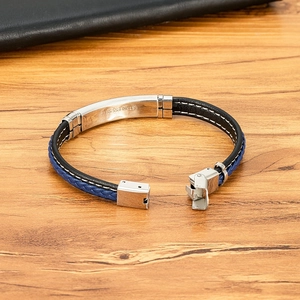 Herenarmband van gevlochten leer met roestvrijstalen plaat op houten achtergrond