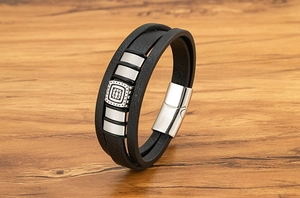 Dettaglio macro del bracciale multistrato in pelle nera da uomo con ciondolo in metallo