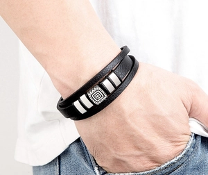 Dettaglio di un bracciale da uomo multistrato in pelle nera con fibbia quadrata incisa argento