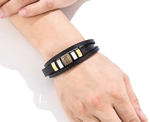 Dettaglio macro del bracciale multistrato in pelle nera da uomo con inserto quadrato dorato