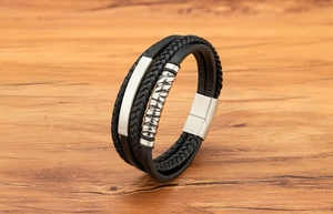 Detail eines mehrlagigen schwarzen Lederarmbands für Herren mit Wellengravur-Metall