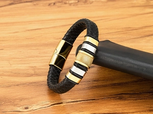 Detail of men's braided leather bracelet with gold magnetic clasp and textured metal ring
