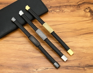 Braided leather bracelets in gold, silver and black metal colors on a wooden background