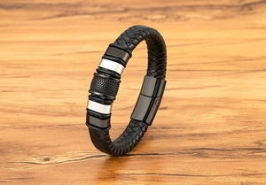 Detailed close-up of men's black braided leather bracelet with textured metal rings