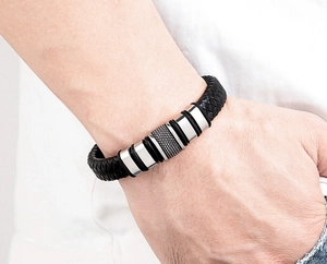 Close-up of men's braided black leather bracelet with textured stainless steel buckle