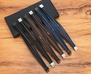 Detail of multi-layer braided leather bracelets with various metal clasps on a wood surface
