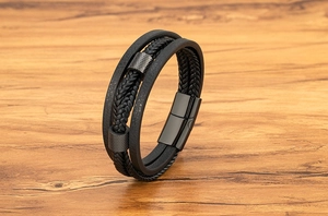Detail eines mehrlagigen schwarzen Lederarmbands mit gerändelten Metallzylindern