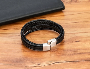 Macro detail of multilayer black leather woven bracelet with silver brushed magnetic clasp