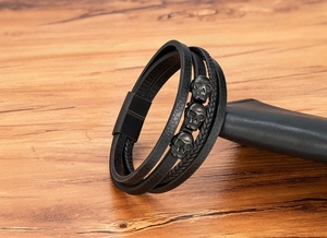 Detail eines mehrlagigen schwarzen Lederarmbands mit drei Metallschädeln und Magnetverschluss